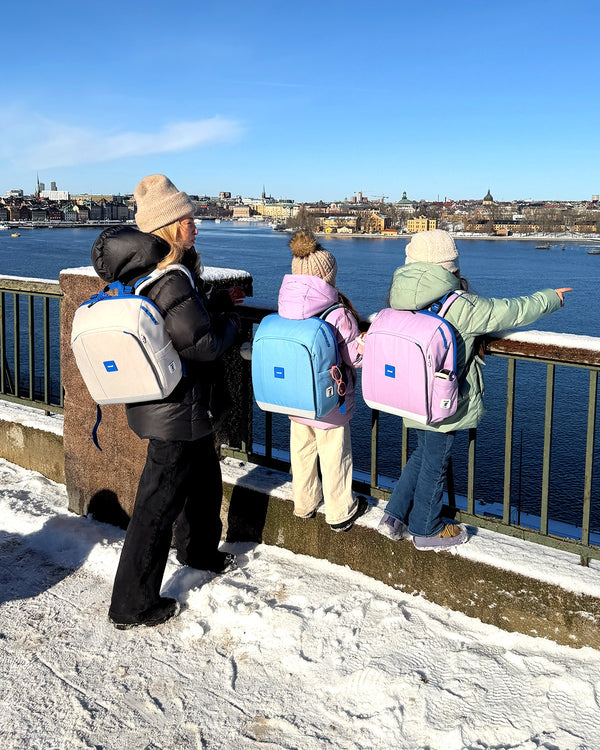 Barn med Rionell Tryggve-ryggsäckar vid Stockholms skyline