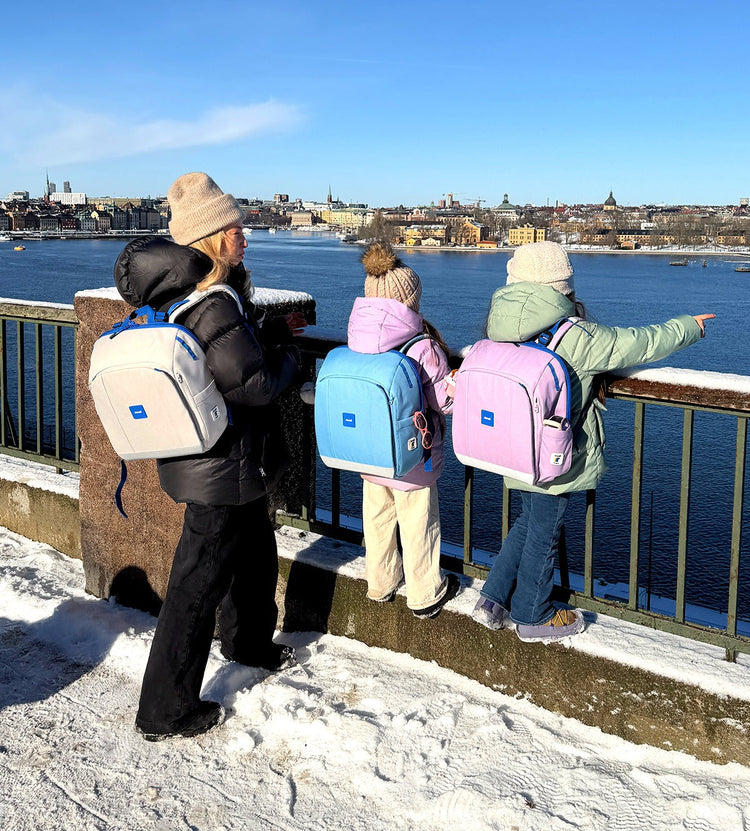 Barn med Rionell Tryggve-ryggsäckar vid Stockholms skylin